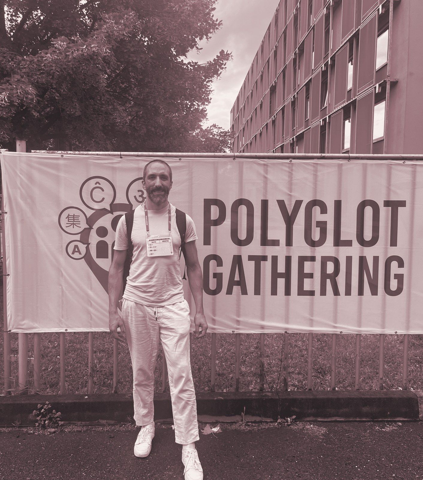 Walter standing in front of a Polyglot Gathering banner.