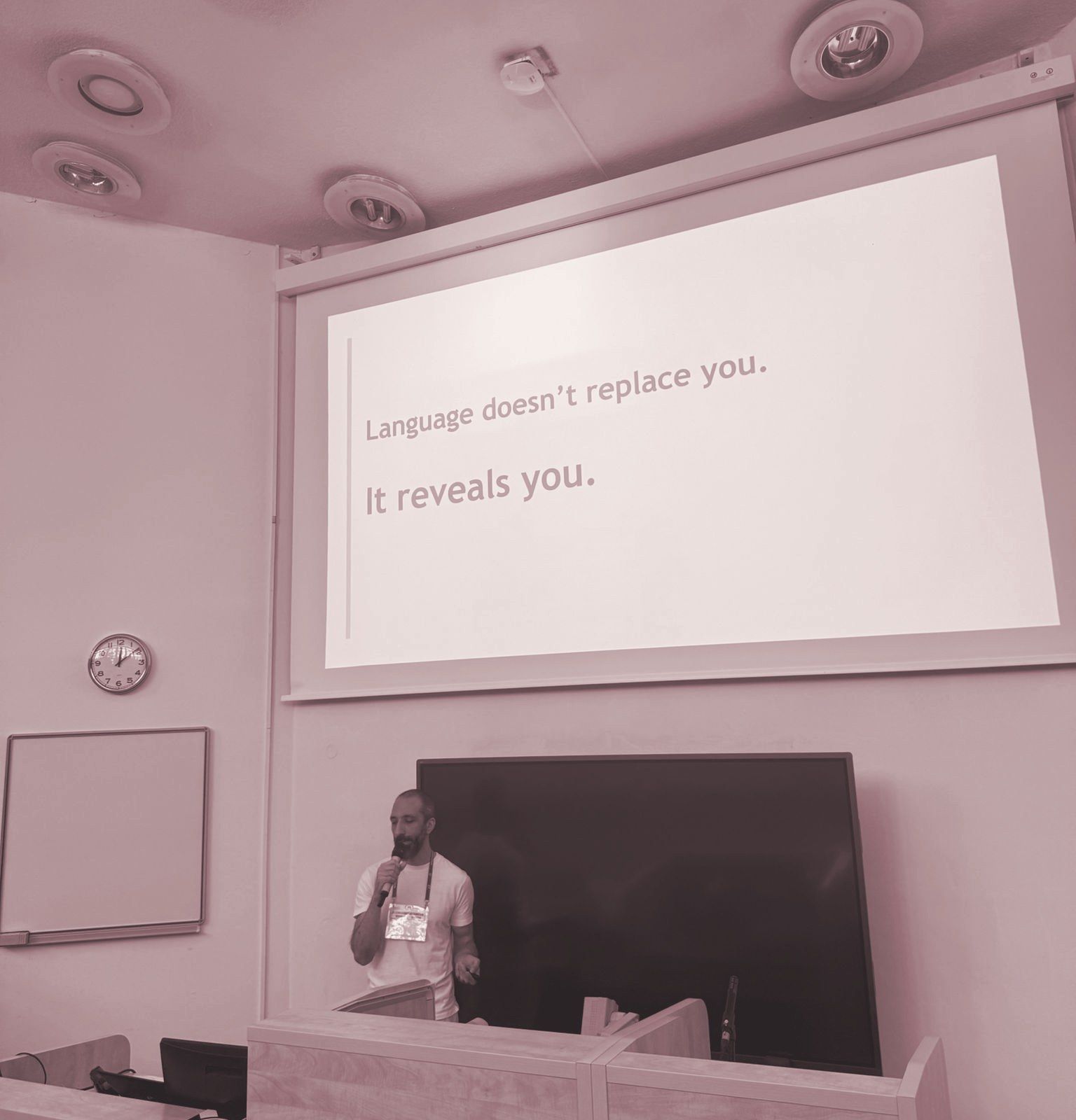 Walter speaking in a lecture hall. The slide behind him reads: Language doesn't replace you. It reveals you.